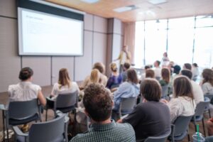 Attendees,Sit,Attentively,As,Speaker,Presents,During,Business,Conference.,Bright,